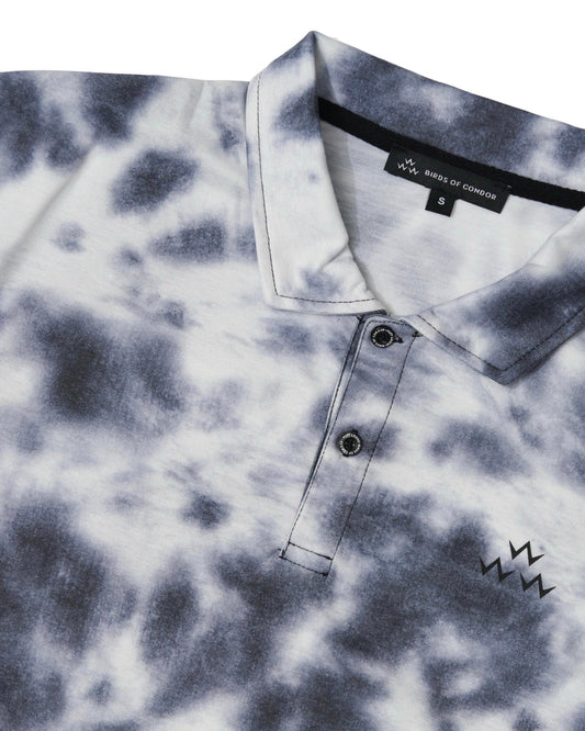 Detail of a black tie-dye polo shirt featuring a two-button placket and a triple eagle print.