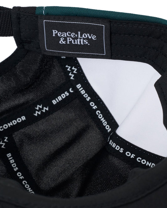 Detail of a white, black, and green cap with interior branded tape reading Peace, Love & Putts.