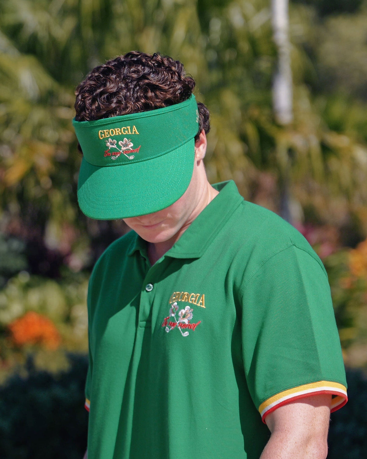 A person wearing a Masters Green tour visor with an embroidered Georgia logo on the front band.