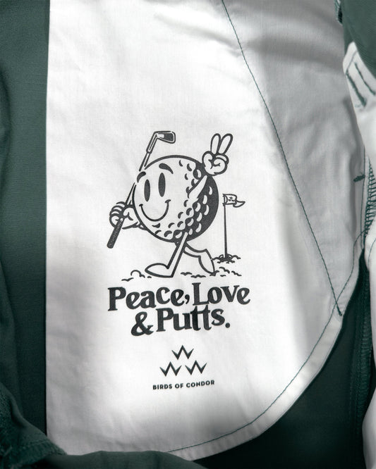 Detail of khaki green shorts with a white printed inner pocket featuring a smiling golf ball holding a club.