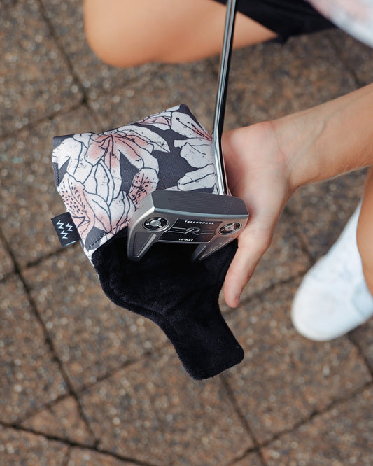 An azalea print mallet putter headcover with a black inner lining, held by a golfer.