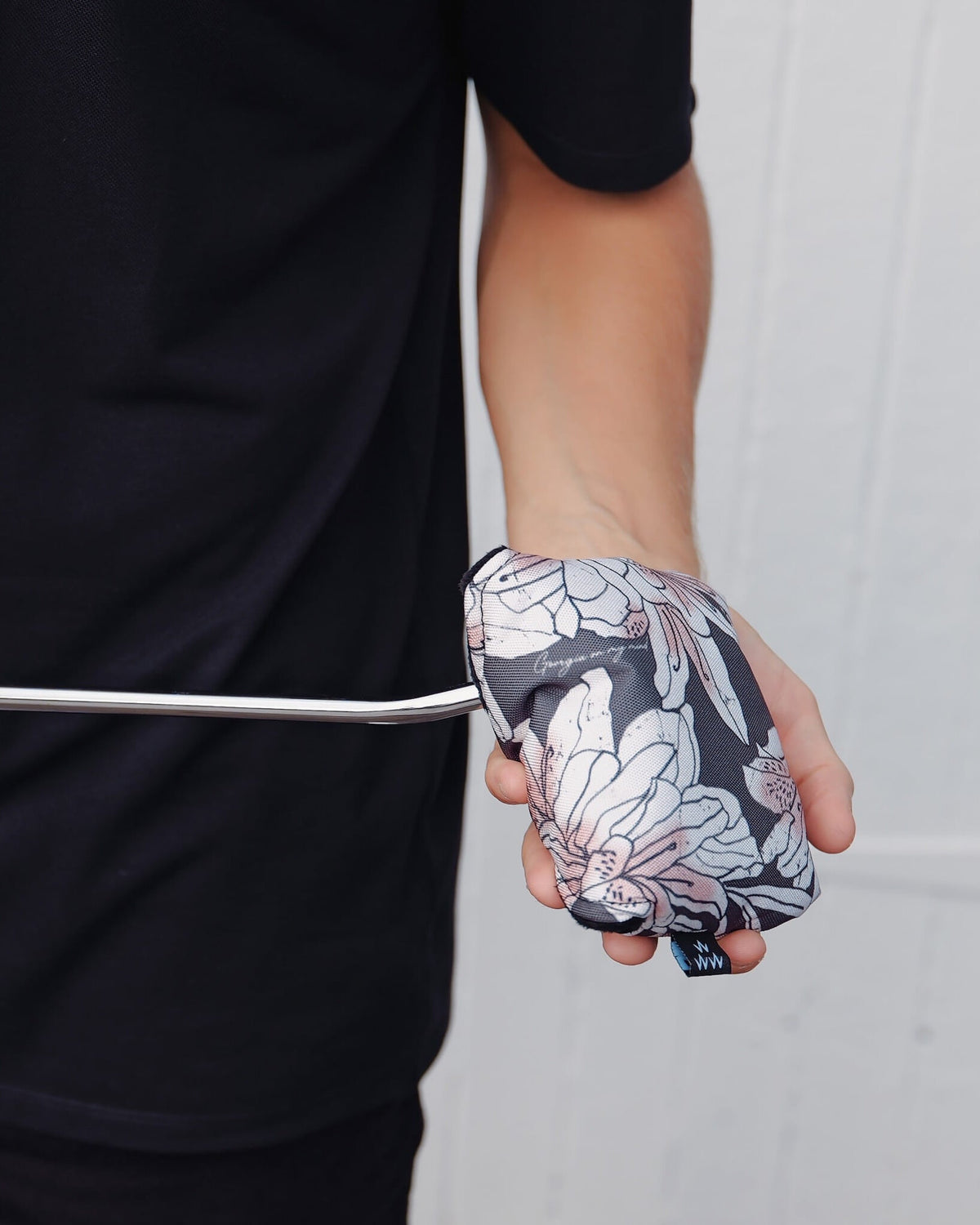 A person holding an azalea-print mallet putter headcover featuring a floral design and script text.