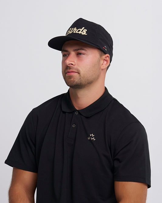 A man wearing a black snapback cap with an off-white script print and a curved brim.