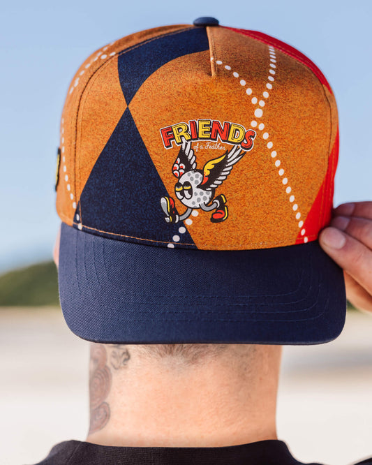 A person wearing an argyle snapback with a navy brim and a winged golf ball graphic on the front.