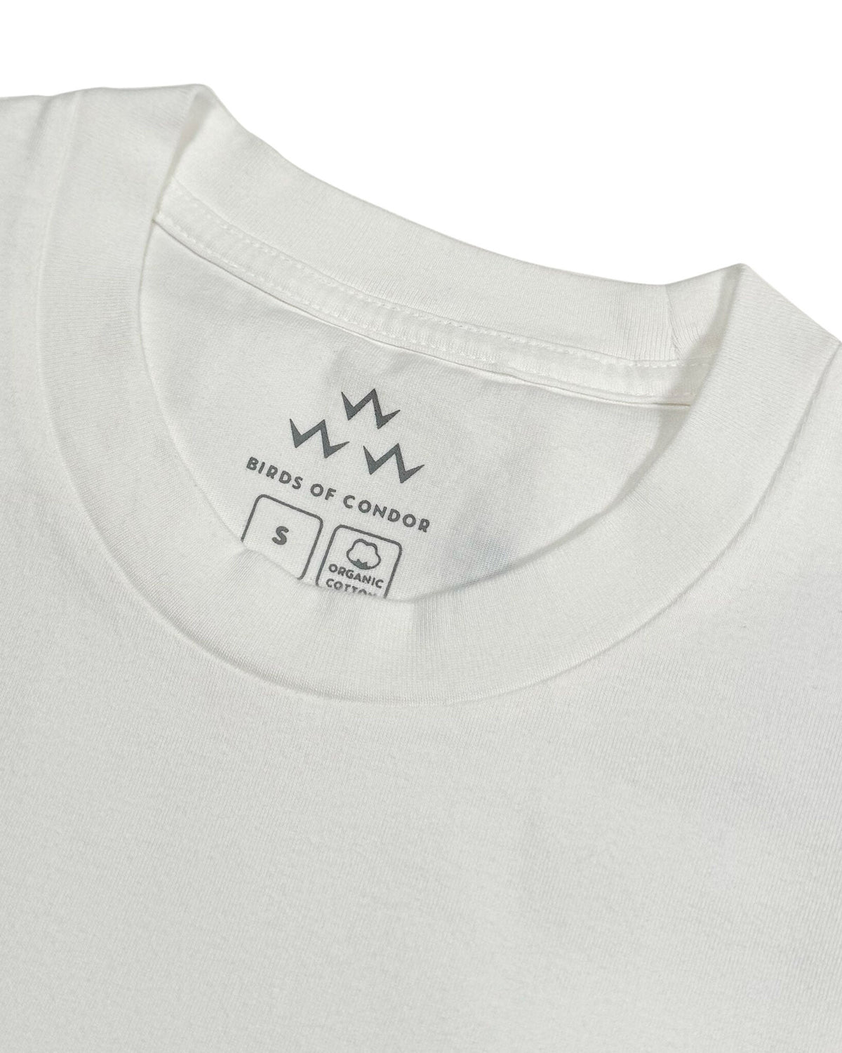 Detail of the white crew neck t-shirt collar showing the printed brand logo and size tag on the inside.