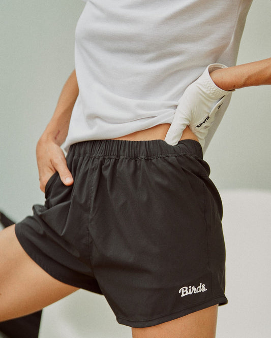 A woman wearing black shorts featuring an elastic waistband and a white script Birds design.