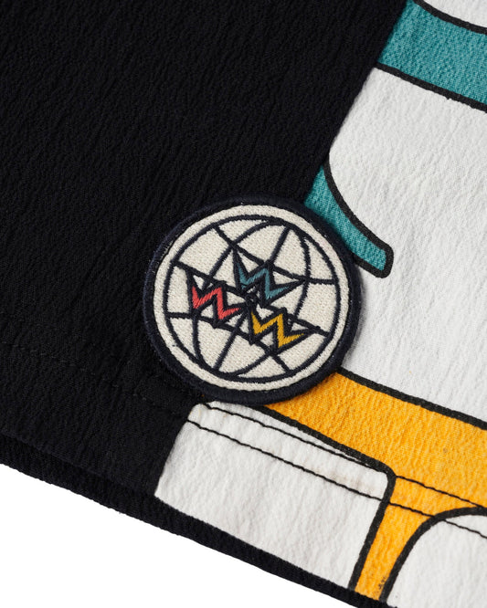 Detail of black and white shorts featuring a round global patch and panelled side leg design.