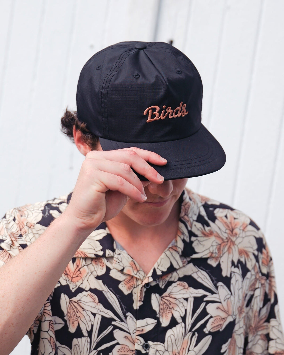A man wearing a black snapback cap featuring embroidered script across the front.
