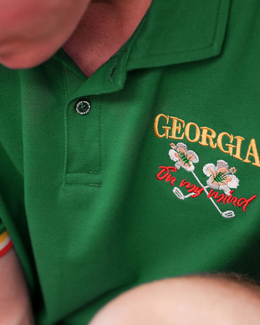Detail of a Masters Green polo shirt featuring an embroidered Georgia On My Mind logo and tri-colour cuffs.