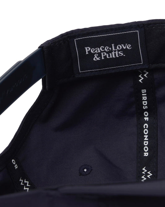 Detail of the interior of a navy cap, showing a branded label reading "Peace, Love & Putts."