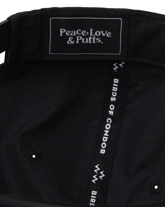 Detail of the interior of a black nylon cap showing the logo text Peace, Love & Putts on the inner taping.