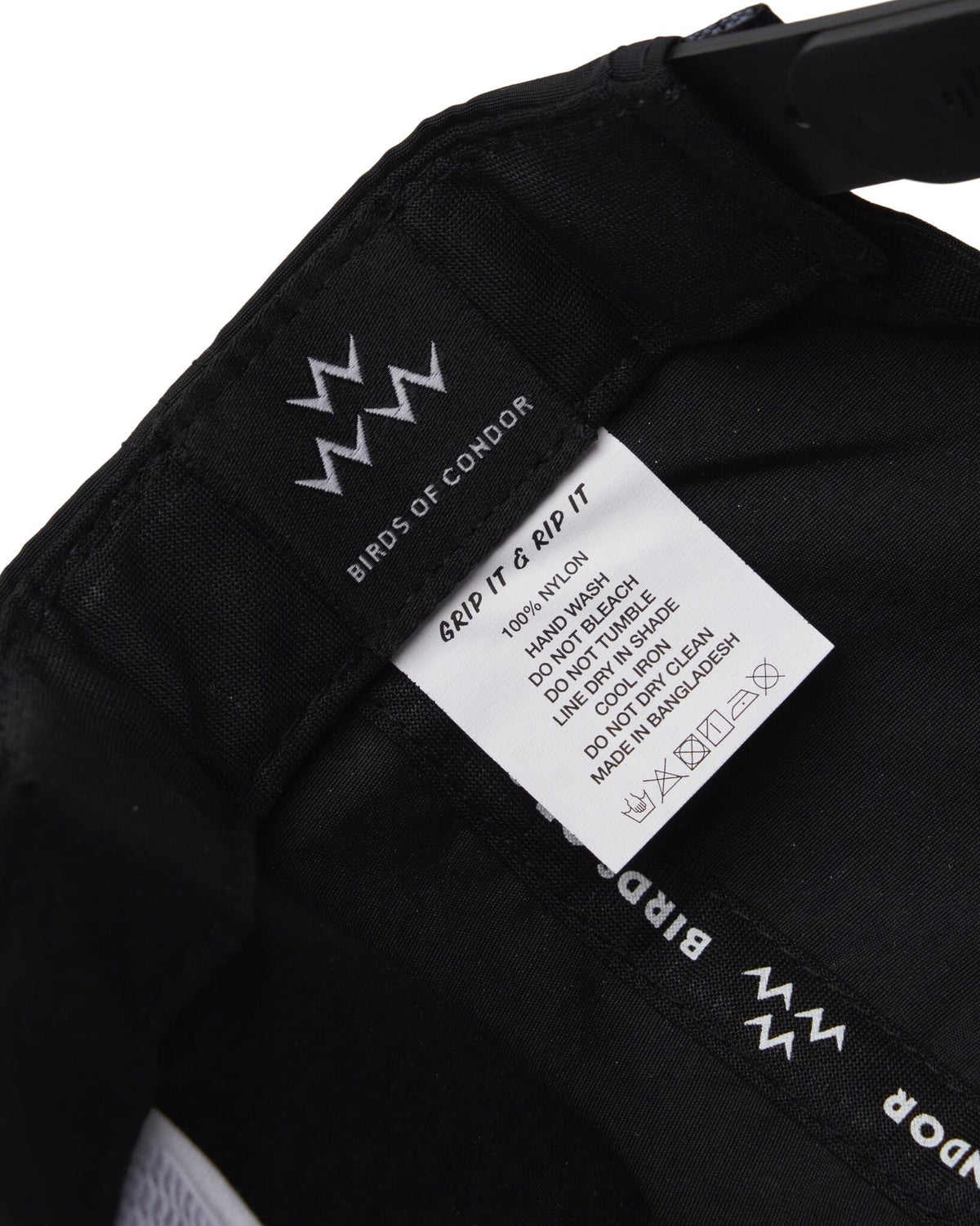 Detail of the inside of a black cap, showing a brand tag and a care label.