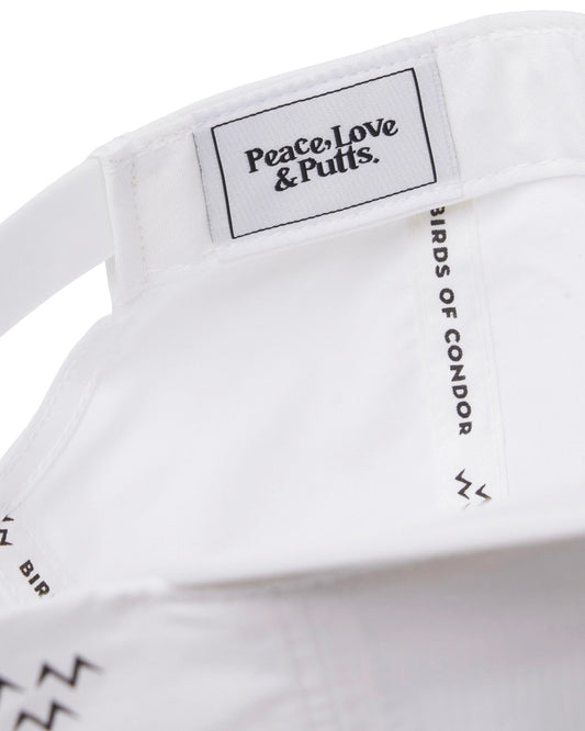 Detail of the inside of a white nylon cap with a woven logo patch reading Peace Love and Putts.