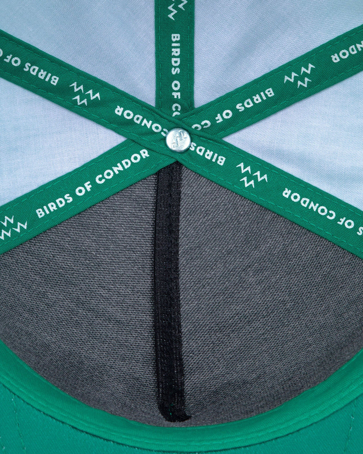 Detail of the interior crown of a green snapback with branded green seam taping and a structured grey front panel.