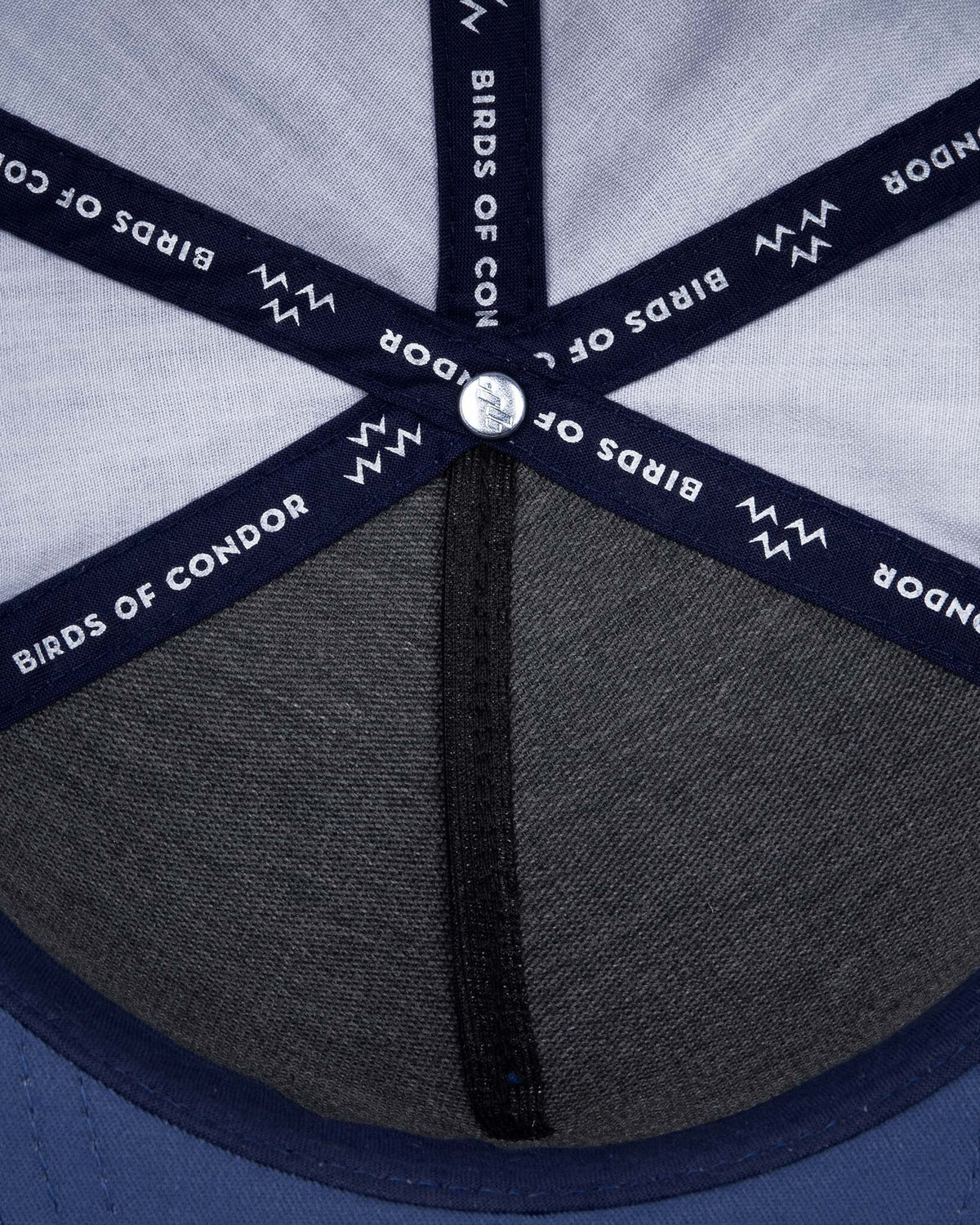 Detail of a navy snapback interior, showing branded seam tape with repeating text and logos.