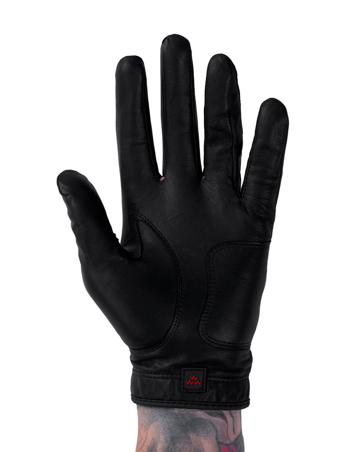 Front of a black leather golf glove with a small red eagle logo on the wrist strap.