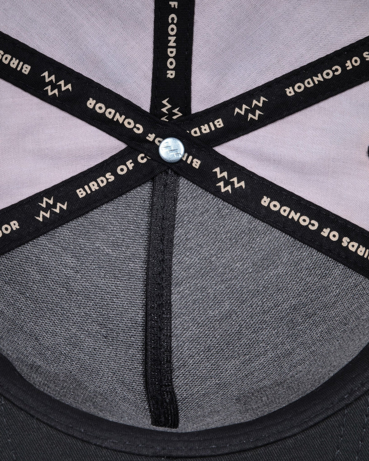 Detail of the interior seams of a black snapback, showing branded black tape with white text.