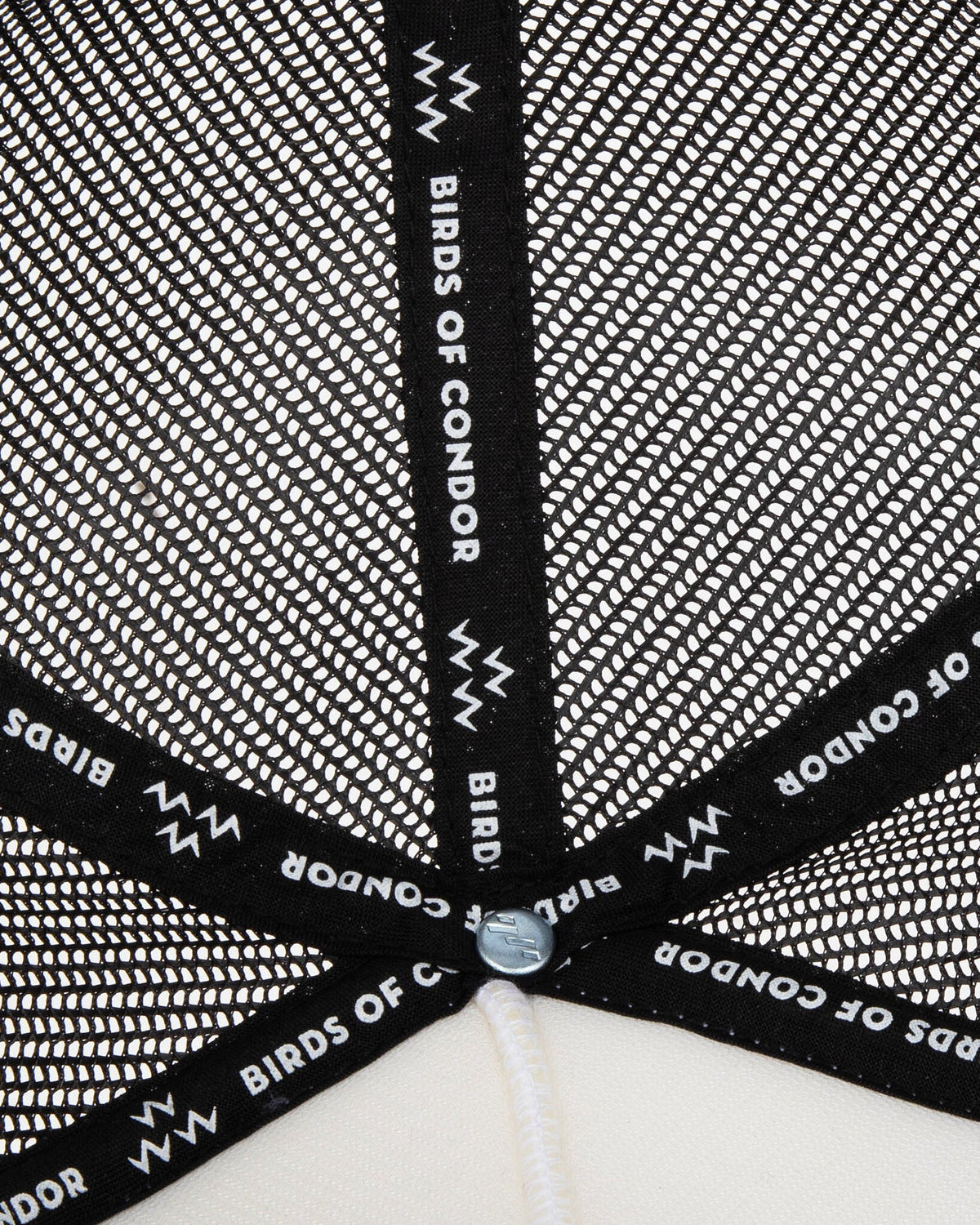 Detail of the black mesh interior of a cap, featuring black interior taping with white text branding.
