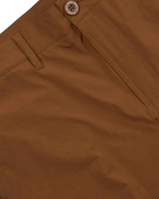Detail of rust shorts featuring belt loops, a tonal front zip, and an embossed button at the waist.