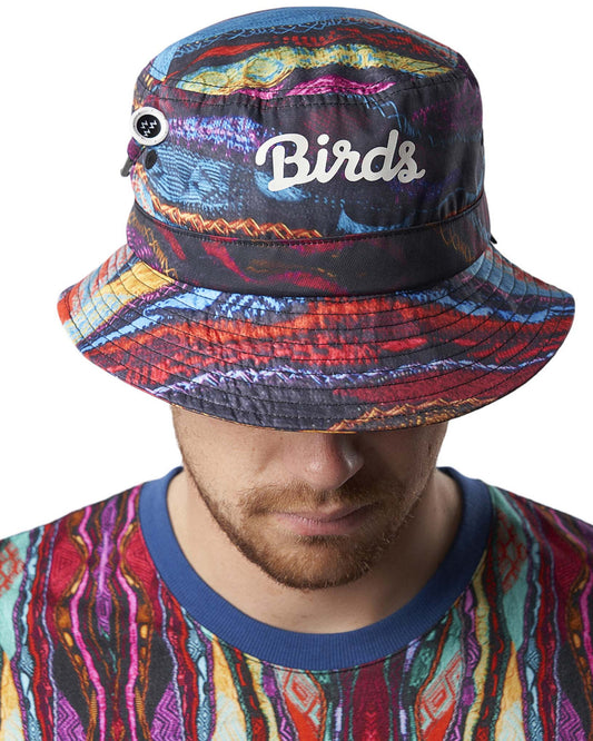 A man wearing a multicolored Coogi print bucket hat featuring a white Birds script logo and tee holder.