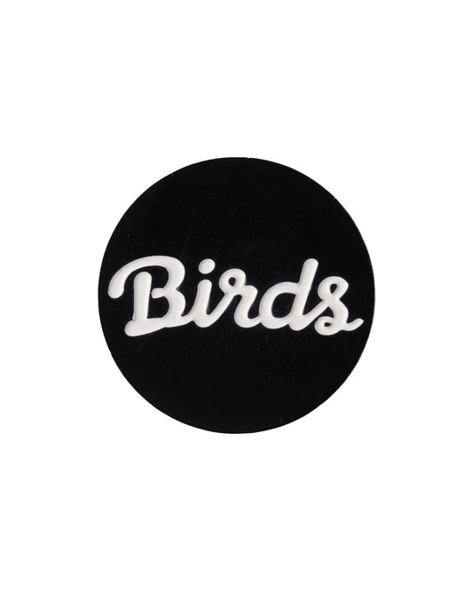 A black golf ball marker featuring the white script graphic Birds across the center.