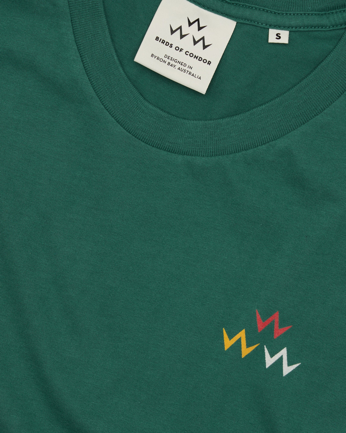 Detail of a green cotton t-shirt featuring a triple eagle logo print and a neck label.