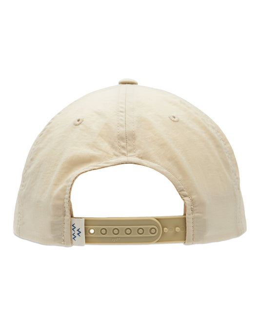 Back of a tan snapback cap with an adjustable plastic strap and a small woven tag showing blue zig-zags.