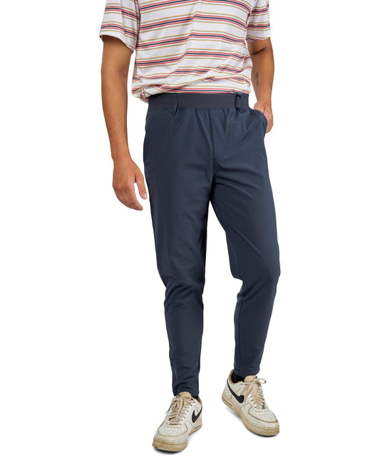 A man wearing navy stretch pants with an elastic waistband, belt loops, and slightly tapered ankles.
