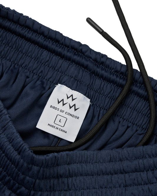 Detail of navy mesh shorts showing an elastic waistband, black drawstring, and inner care label.