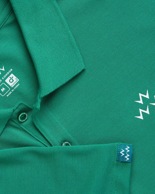 Detail of a green polo shirt featuring a white triple eagle print, ribbed collar, and buttons.