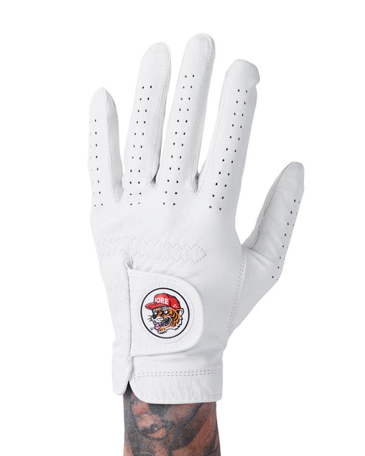 A white golf glove featuring perforated fingers and a circular patch of a tiger wearing a red cap on the velcro strap.
