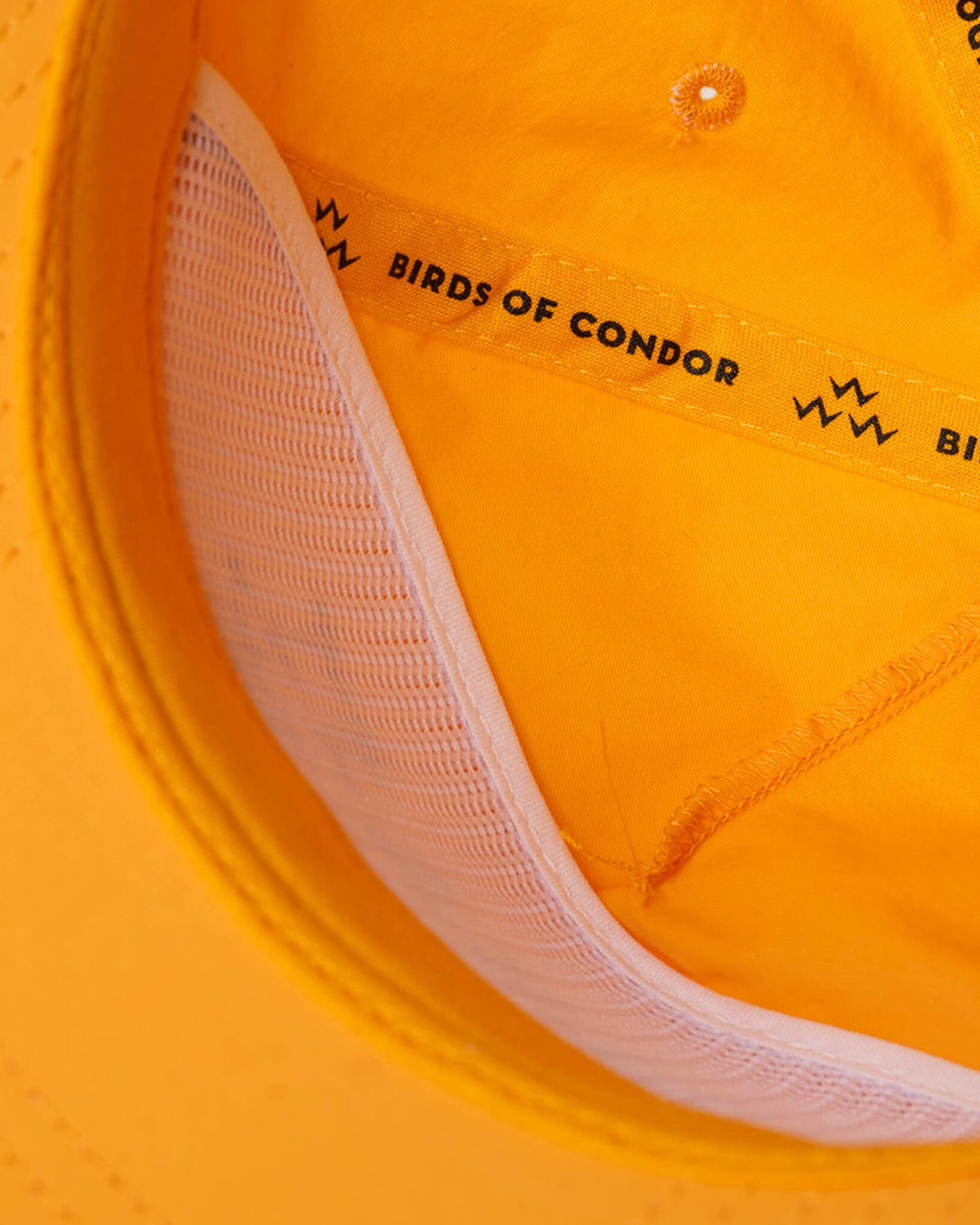 Detail of the yellow snapback's white inner mesh crown and branded tape trim.