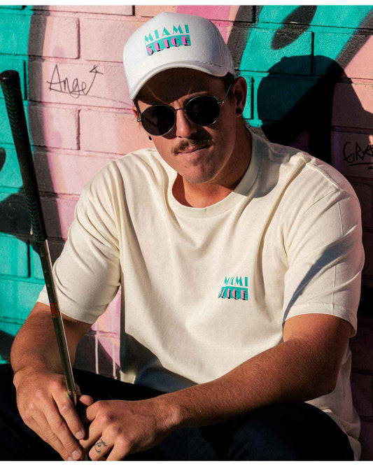 A man wearing a white snapback with a turquoise and pink Miami Slice print.