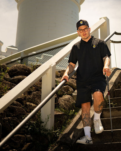 A man walking down stone steps wearing a black quarter zip polo with an embroidered golf ball.