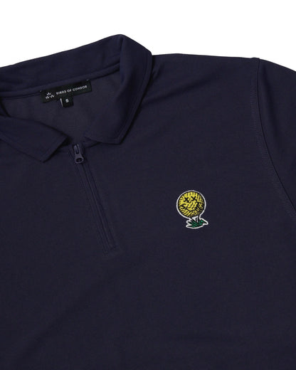 Detail of a navy polo shirt with a quarter zip neckline and an embroidered yellow smiley golf ball motif.