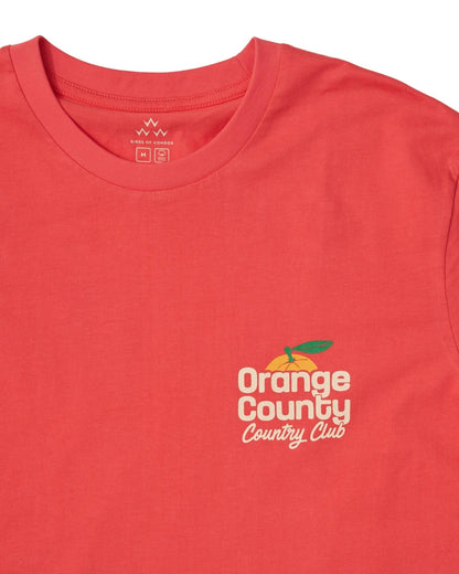 Detail of a blood orange t-shirt with a crew neck and a small front fruit graphic reading Orange County Country Club.