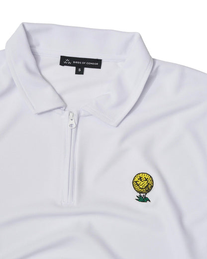 Detail of a white quarter-zip polo shirt with a smiling yellow golf ball motif on the chest.