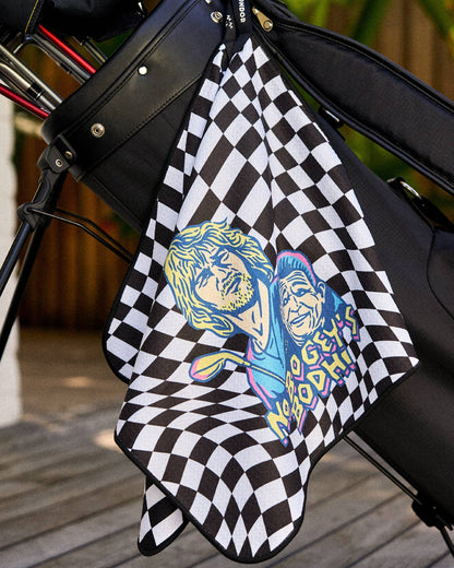 A black and white checkered golf towel hangs from a golf bag, featuring a colorful surfing graphic.