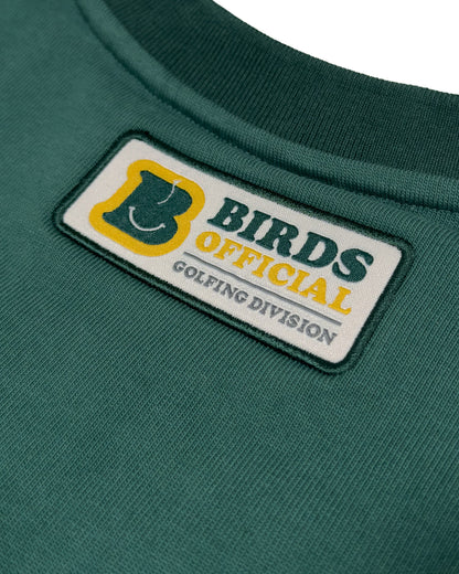 Detail of a green cotton sweater featuring a rectangular patch with Birds Official Golfing Division text.
