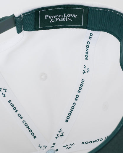 Detail of a white snapback's interior, showing green inner taping with Peace, Love & Putts lettering.