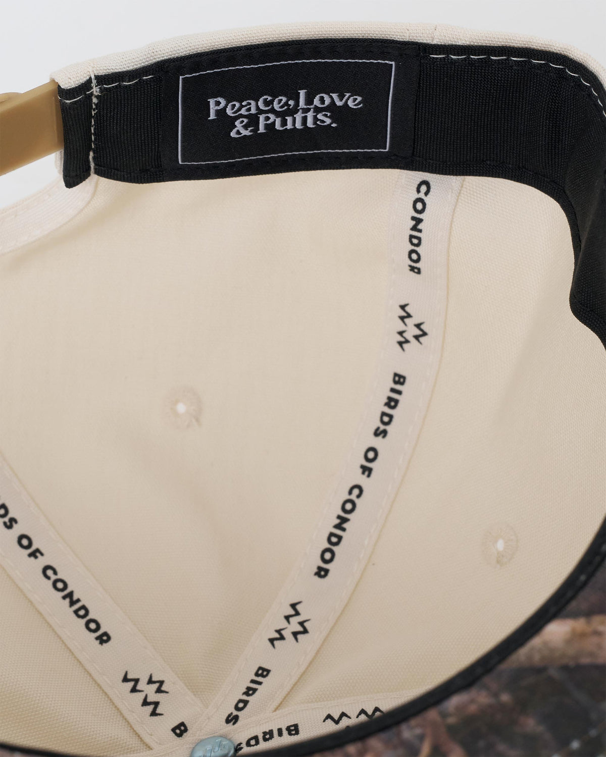 Detail of a natural snapback interior, featuring a woven black logo patch and branded inner taping.