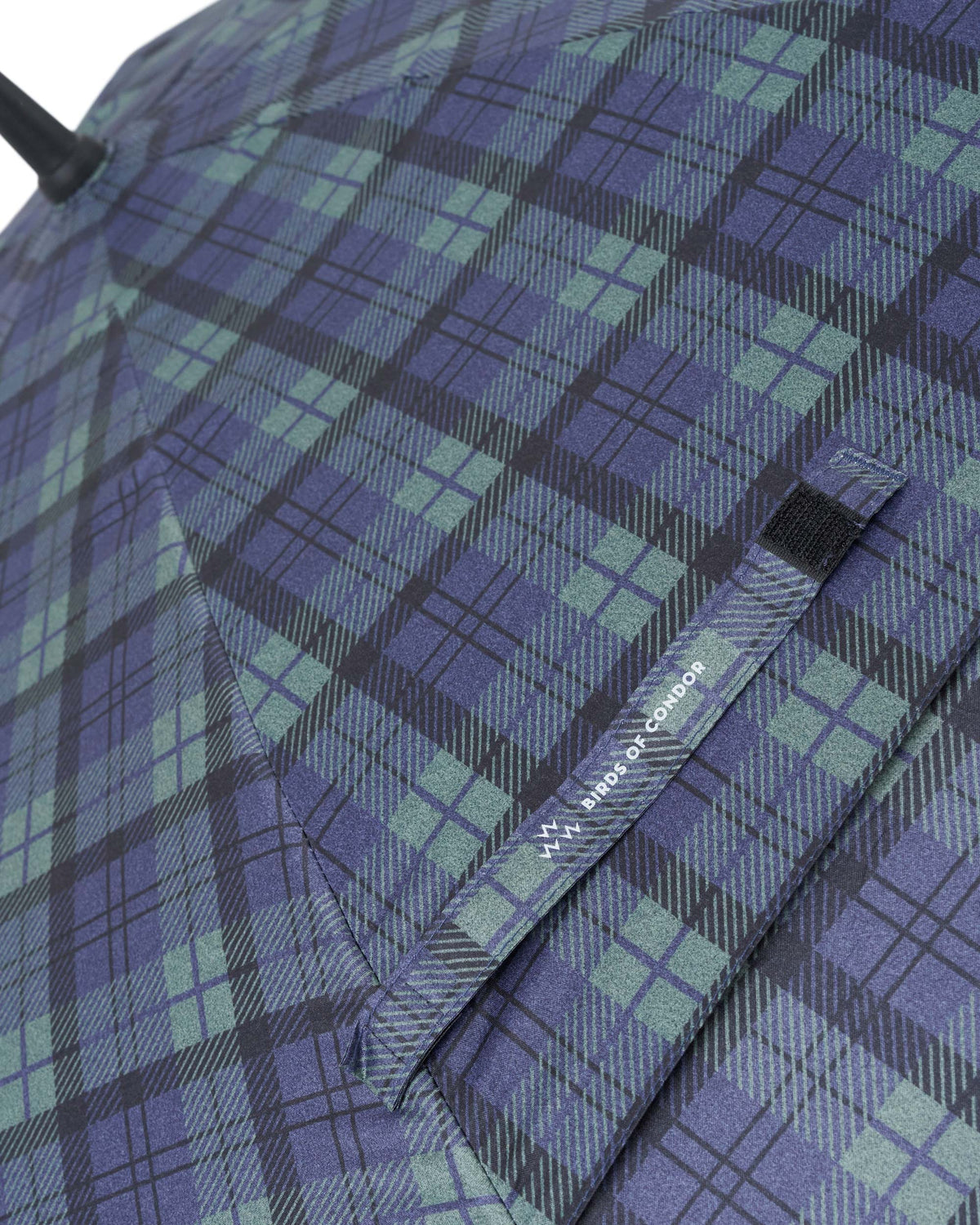 Detail of blue and green plaid umbrella with a branded velcro tie strap.