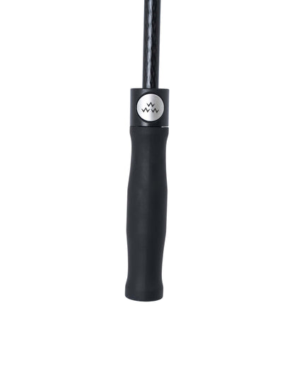 Detail of a black umbrella handle with a silver round pop button bearing a three-pronged crown logo.