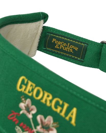 Detail of a Masters green cotton twill visor with yellow Georgia text, pink flowers, and a woven inner tag.