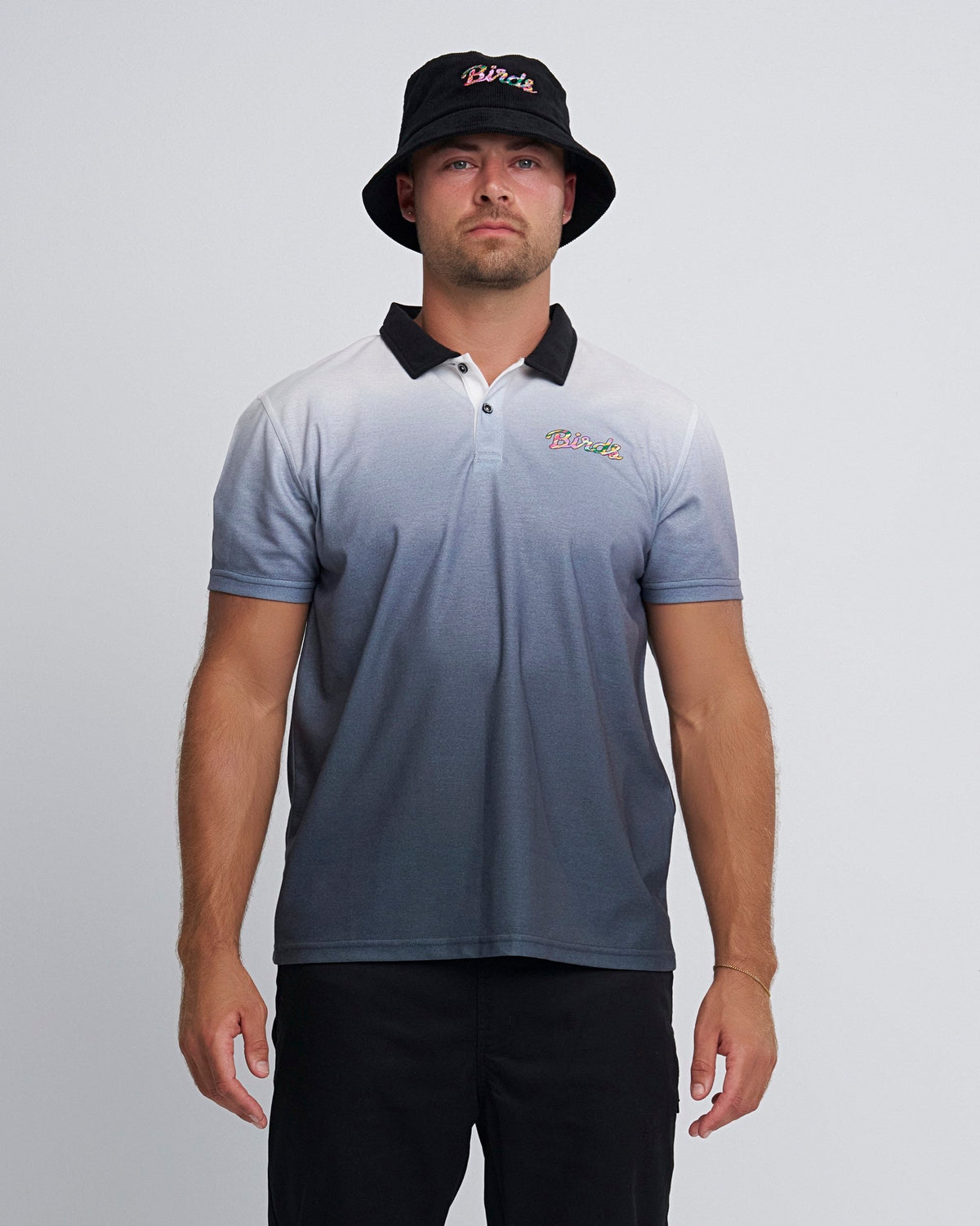 A man wearing a black gradient polo shirt with a black collar, three buttons, and a left chest bird graphic.