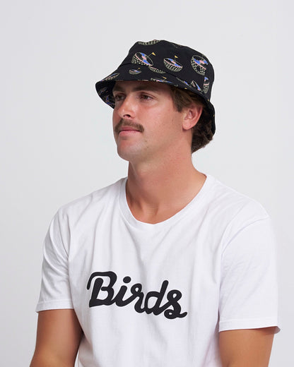 A man wearing a black bucket hat with an all-over checkered golf hole graphic print.
