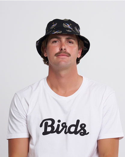 A man wearing a black bucket hat with an all-over golf ball graphic, and a white t-shirt.