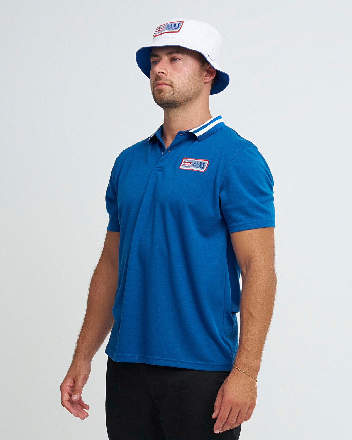 A man wearing a blue polo shirt with a white striped collar and a chest patch, plus a matching hat.