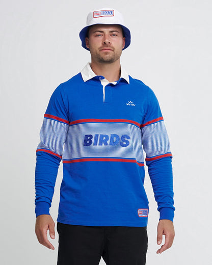 A man wearing a blue cotton sweater with a white collar, striped chest panel, and embroidered text.