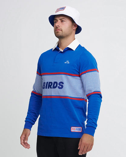 A man wearing a blue cotton sweater with a white collar, striped chest panel, and embroidered front text.